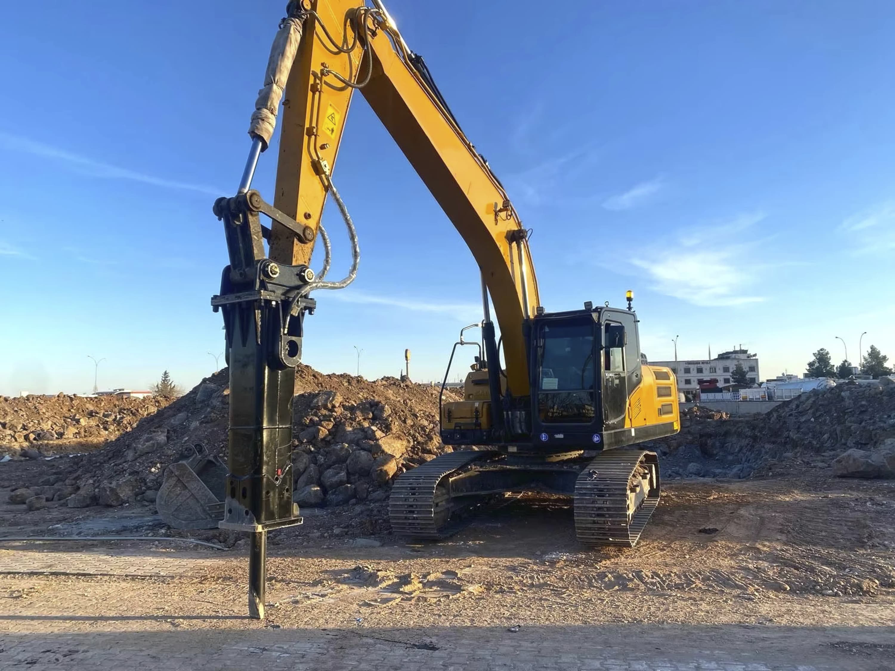 Un brise-roche monté sur une excavatrice sur un chantier, tiré de la brochure DemaRock de la série E